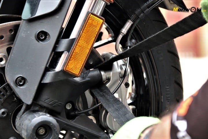 Pasando la cincha por la pinza para atar la moto al remolque 