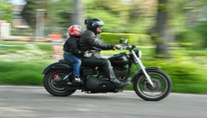niño montado con un adulto en una moto negra